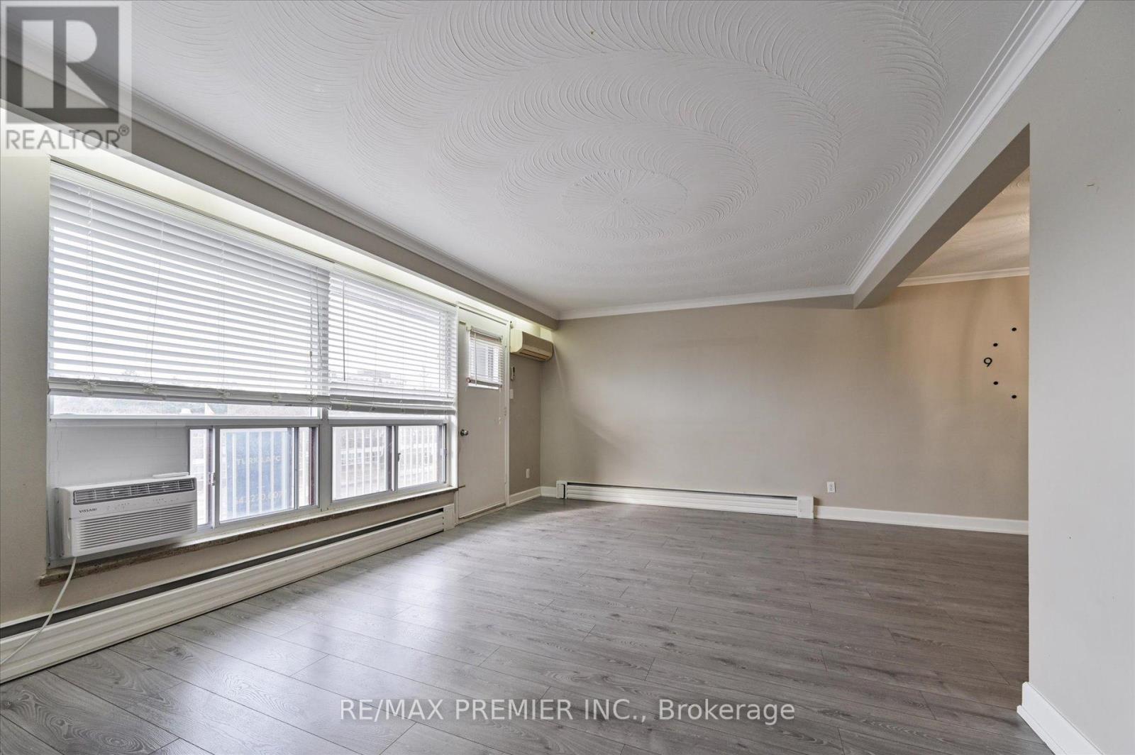 A spacious room with wooden floors and a window with blinds.