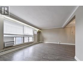 A spacious room with wooden floors and a window with blinds.