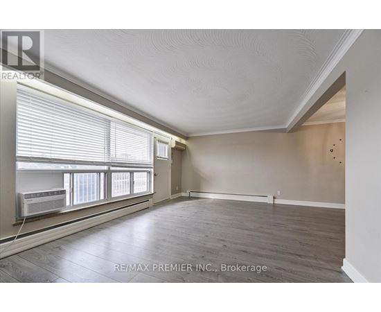 A spacious room with wooden floors and a window with blinds.