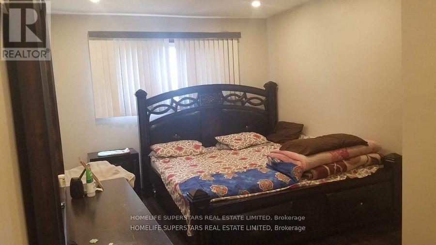 A bedroom with a bed, nightstand, and window with curtains.