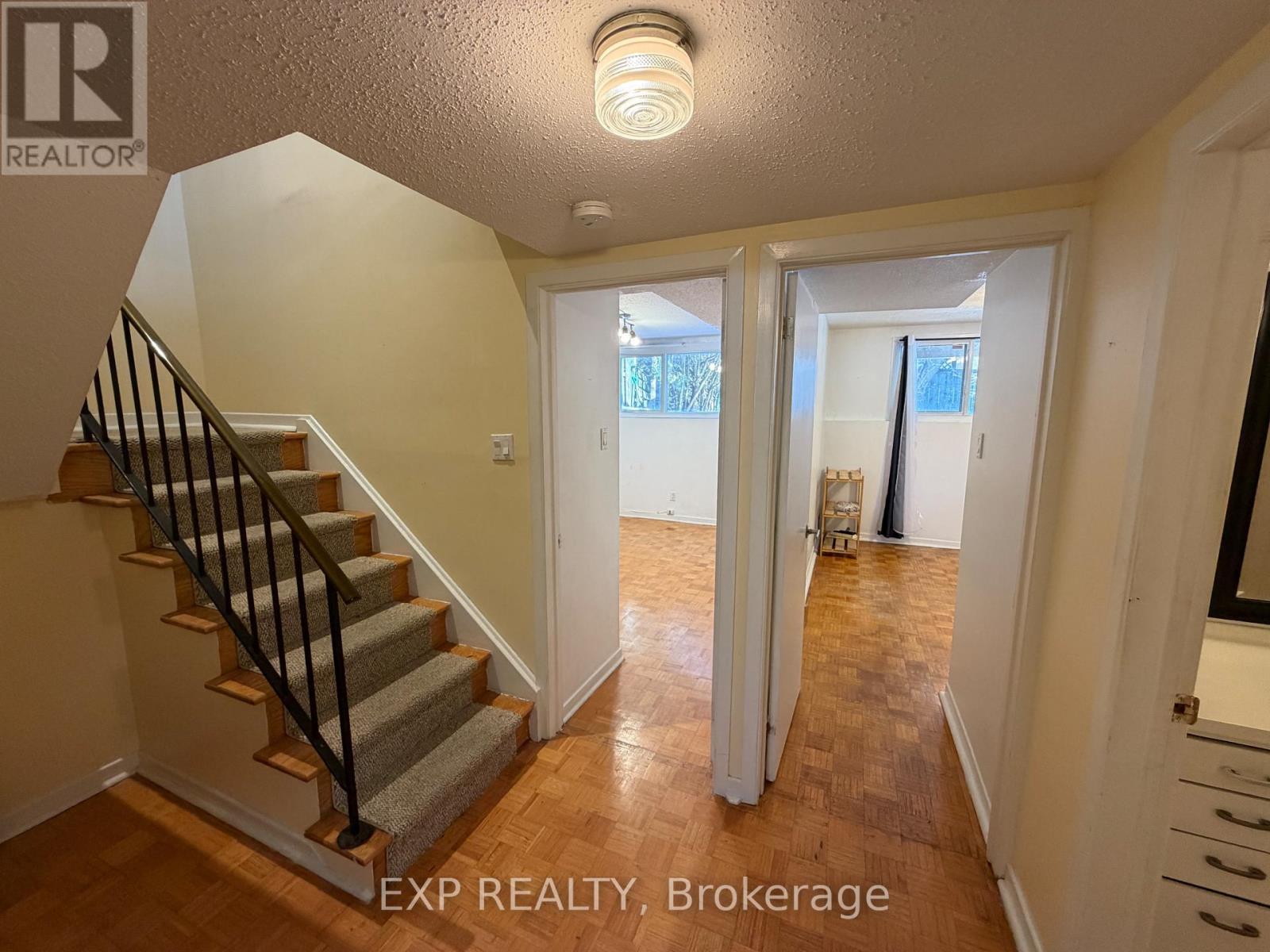 A hallway with a staircase and a door leading to a balcony.