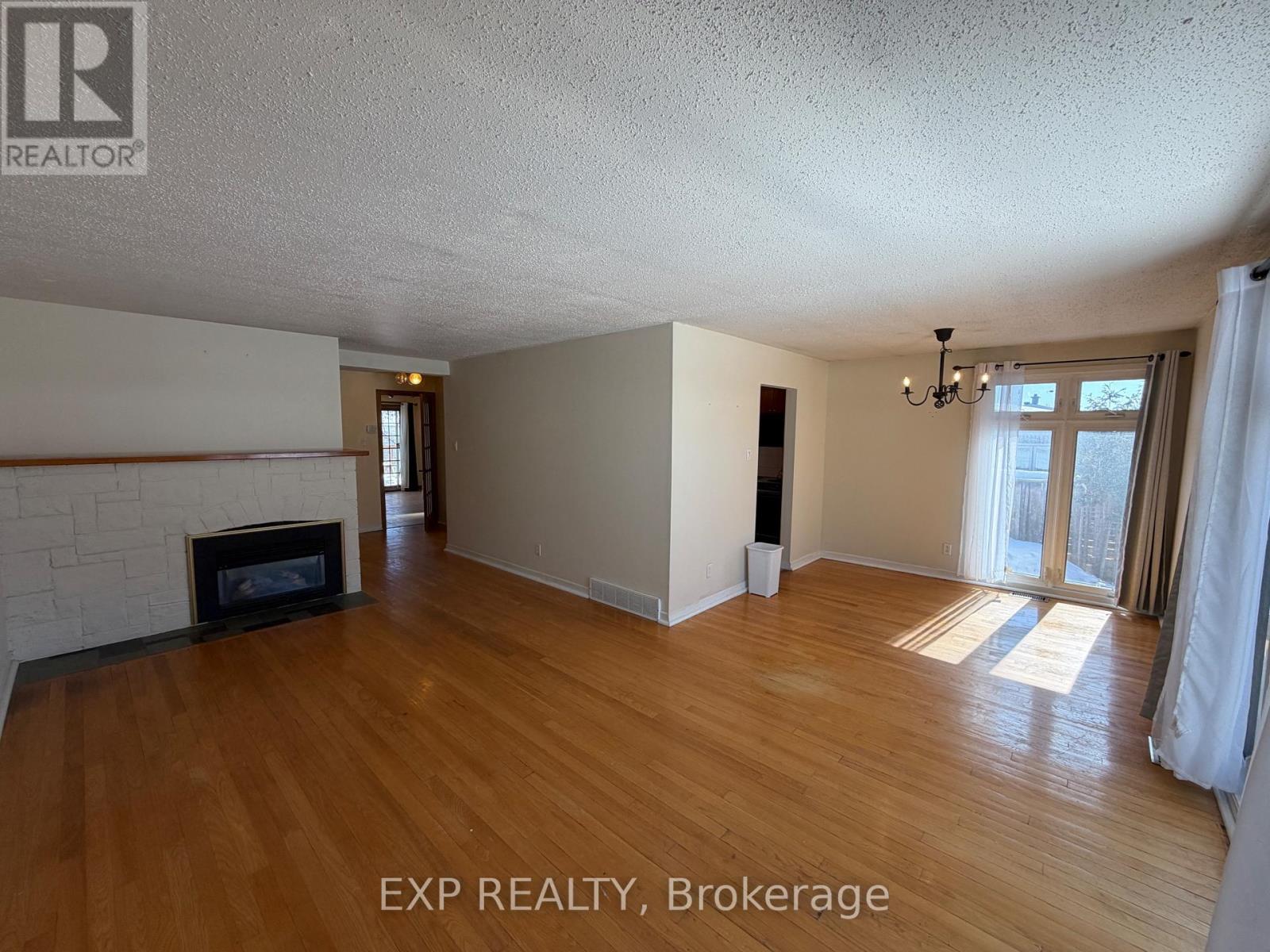 A room with wooden floors and a fireplace is on the market with EXP Realty, Brokerage.