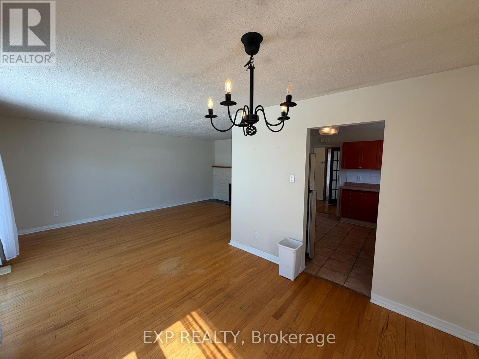 A room with wooden flooring and a chandelier.