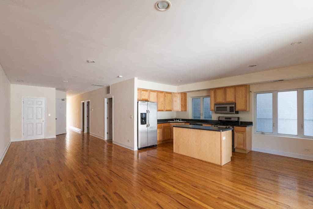 an empty kitchen with wooden floors and a refrigerator
