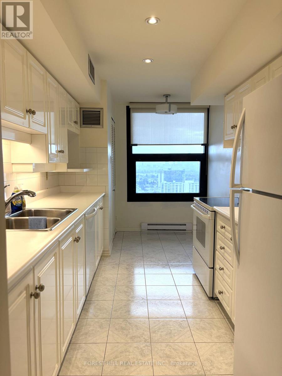 A kitchen with white cabinets and a window overlooking the city.
