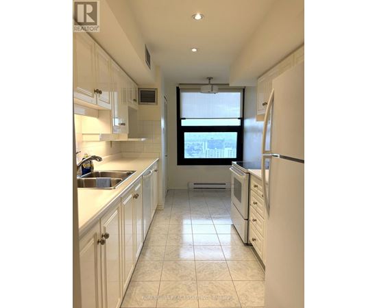 A kitchen with white cabinets and a window overlooking the city.
