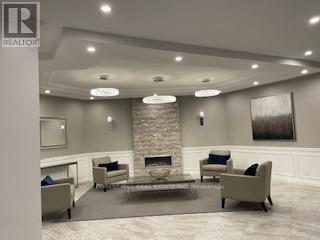 A living room with a stone fireplace and a grey couch.
