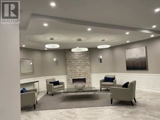 A living room with a stone fireplace and a grey couch.