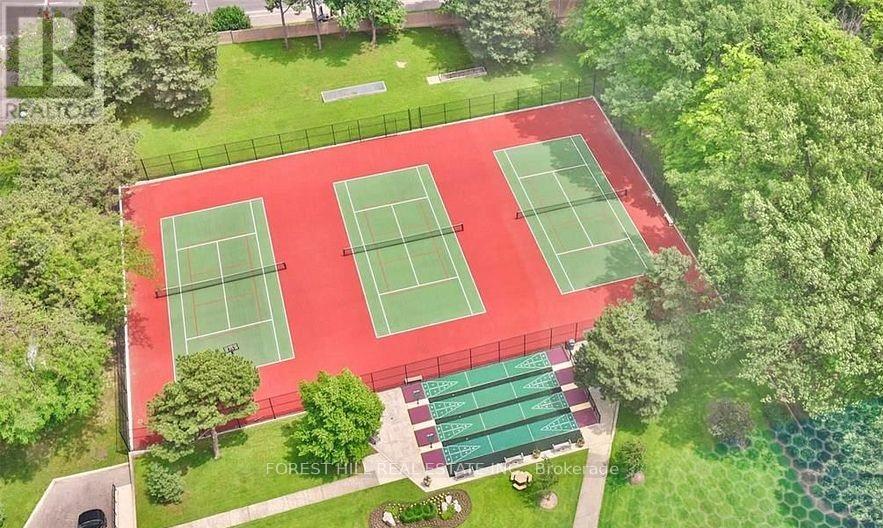 Tennis courts surrounded by green trees and grass.