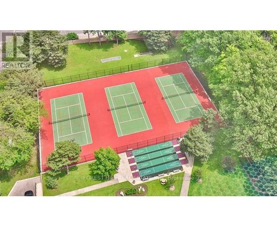 Tennis courts surrounded by green trees and grass.