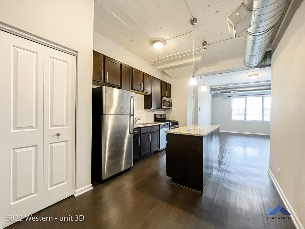 an empty kitchen with stainless steel appliances and wood flooring