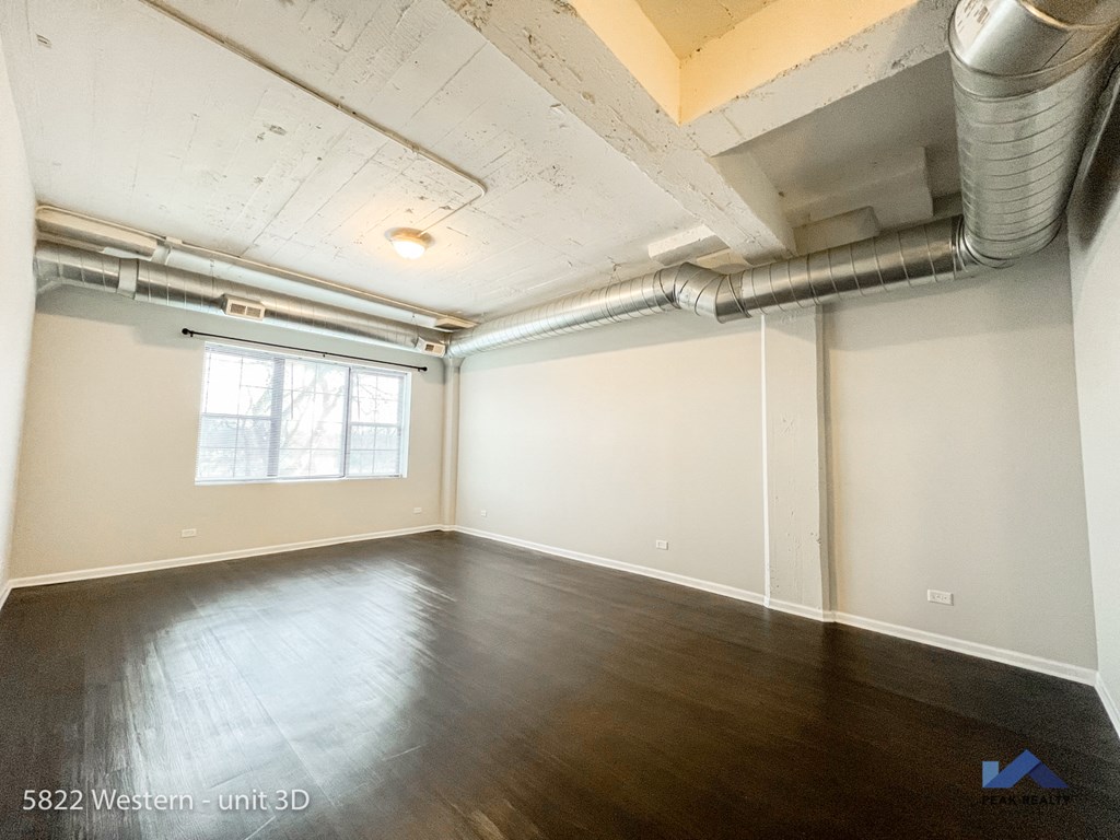 an empty living room with wood floors and a window