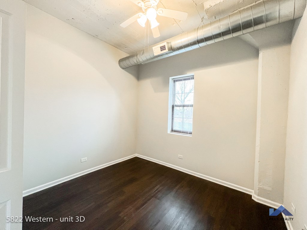 a bedroom with white walls and wood floors and a window