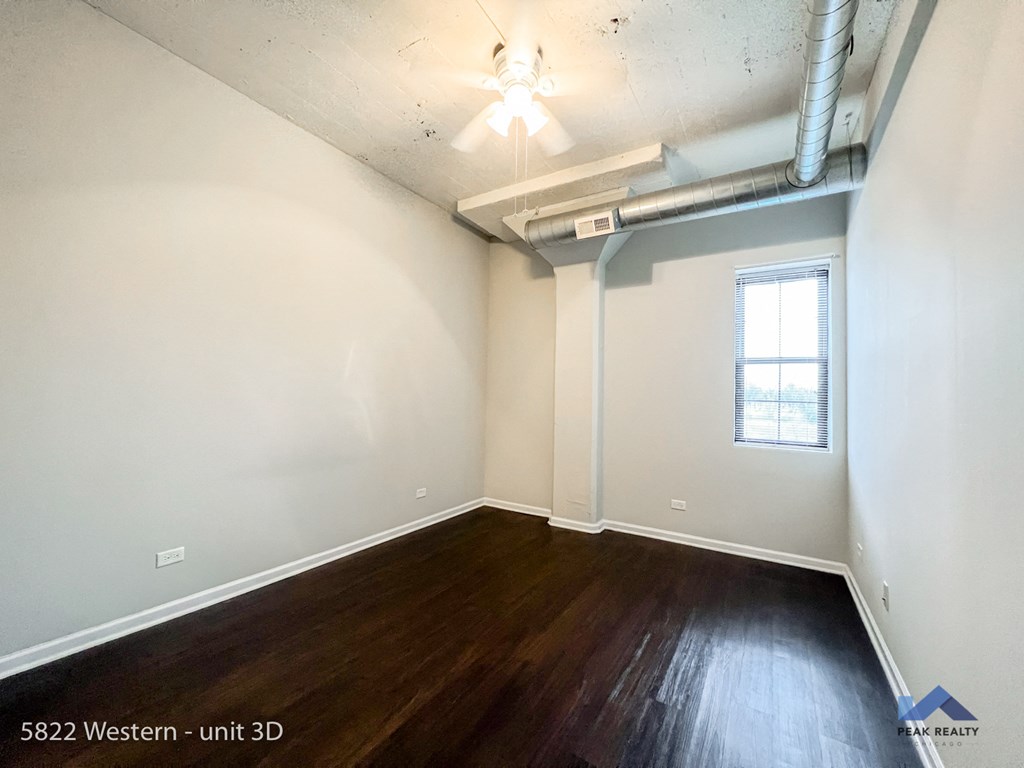 the living room of an apartment with wood flooring and a ceiling fan