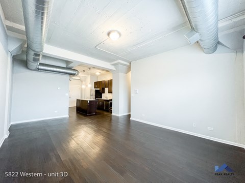 the living room and dining room of an apartment with wood floors and white walls