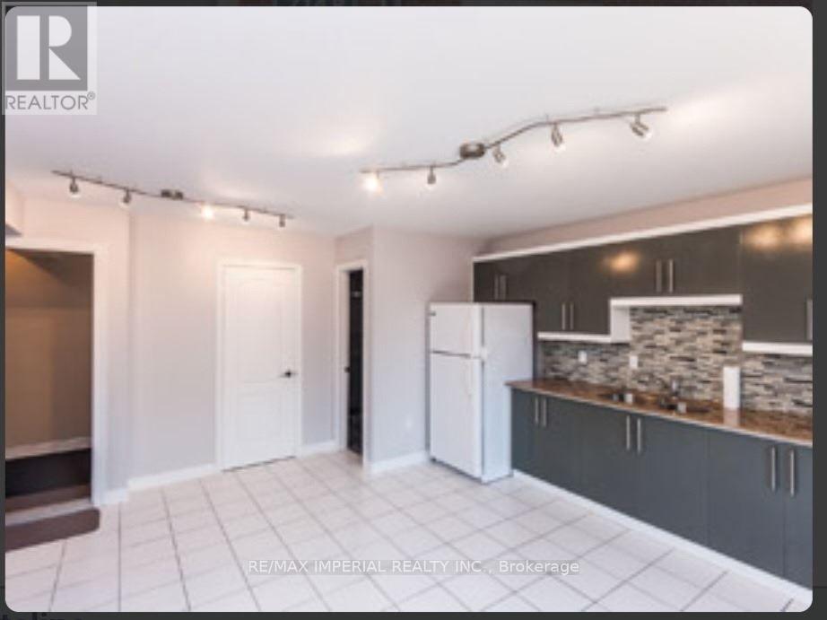 A kitchen area with a refrigerator, cabinets, and a countertop.