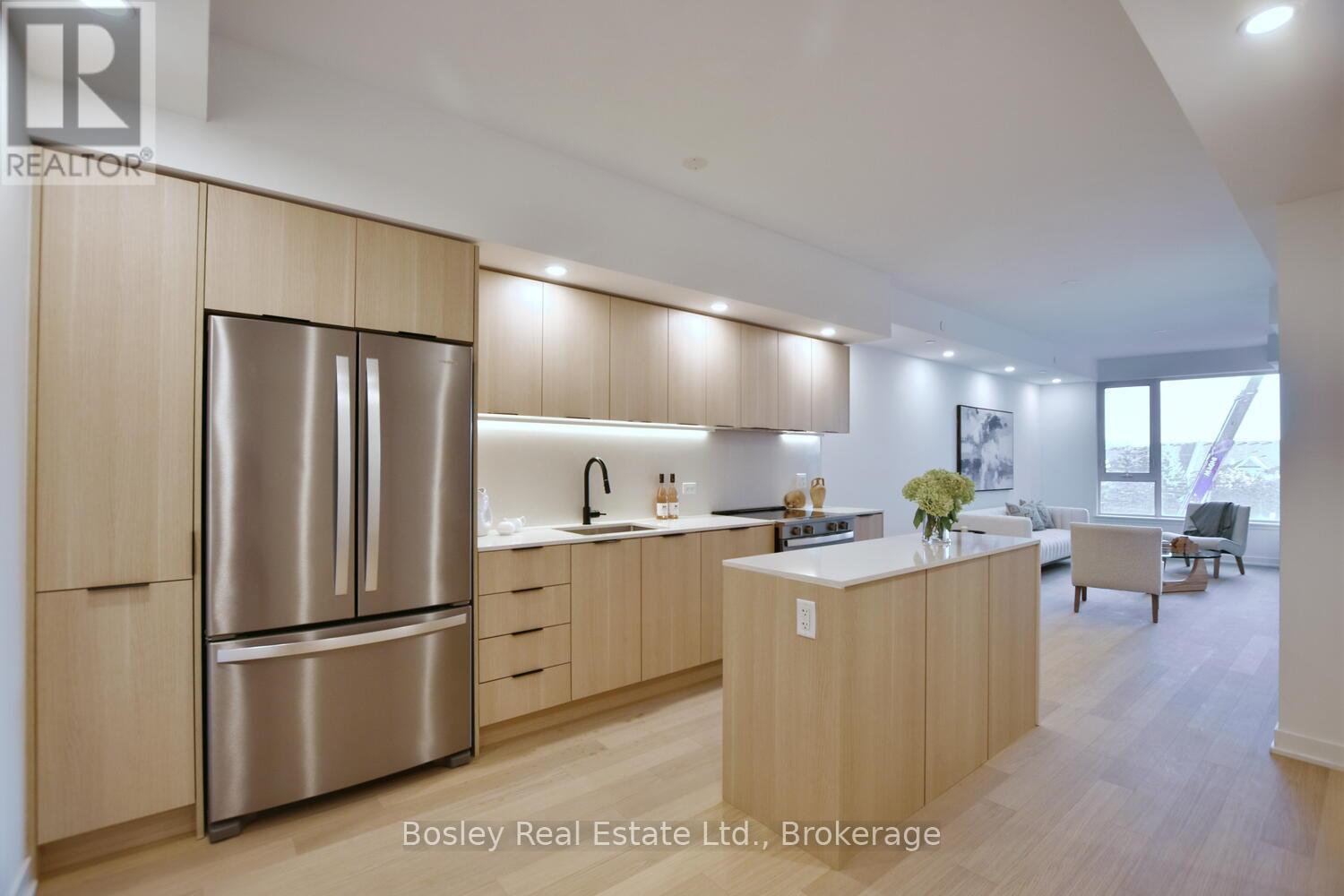 A modern kitchen with wooden cabinets and a stainless steel refrigerator.