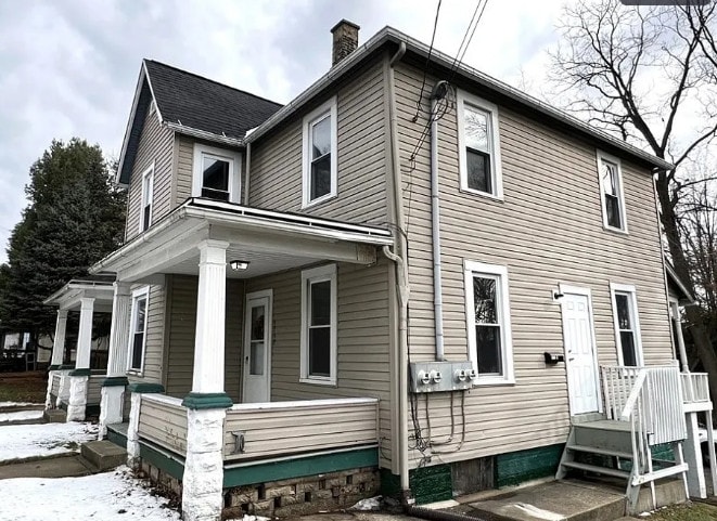A two-story house with a porch and a white door.