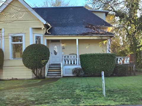 A yellow house with a white door and a sign in front.
