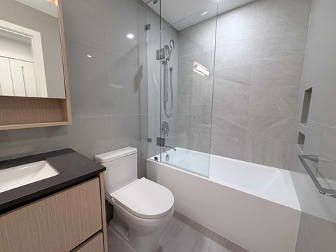 A modern bathroom with a toilet, sink, and bathtub.