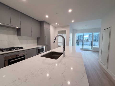 A modern kitchen with a marble countertop and stainless steel appliances.