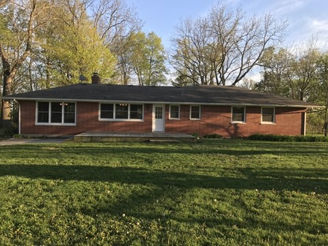 A red brick house with a white door and windows.
