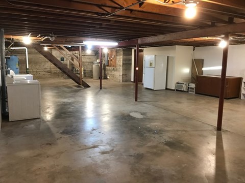A spacious basement with concrete floors and a staircase leading to the upper level.