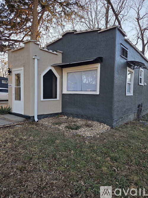 A small house with a grey and beige exterior is shown.