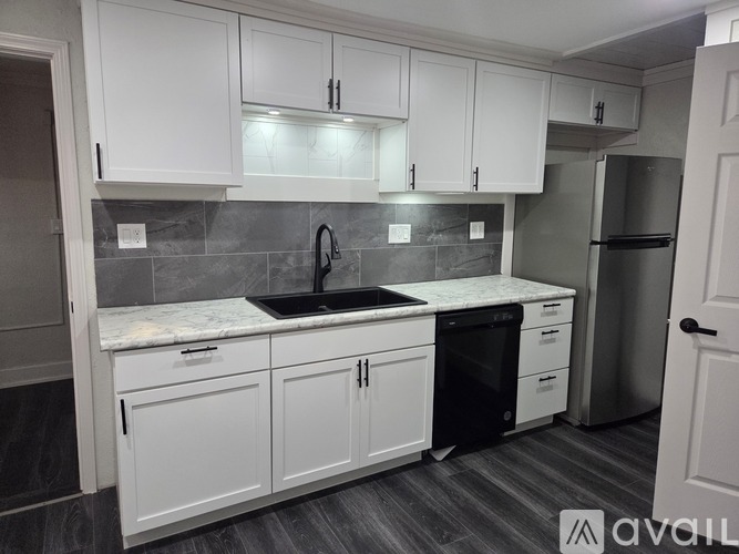 A kitchen with white cabinets and a marble countertop.