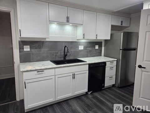 A kitchen with white cabinets and a marble countertop.