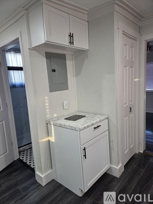 A white kitchen cabinet with a marble top and a small door.