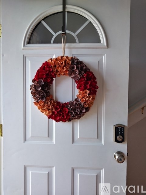 A wreath made of wine corks is hanging on a white door.