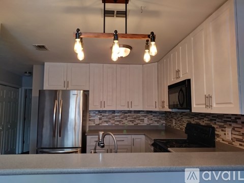 A kitchen with white cabinets and a stainless steel refrigerator.