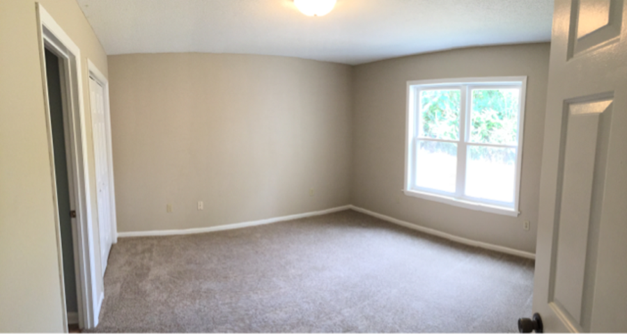 A room with a carpeted floor and a window.