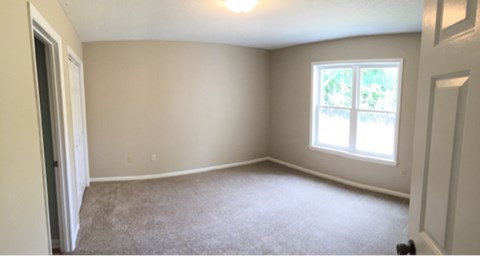 A room with a carpeted floor and a window.
