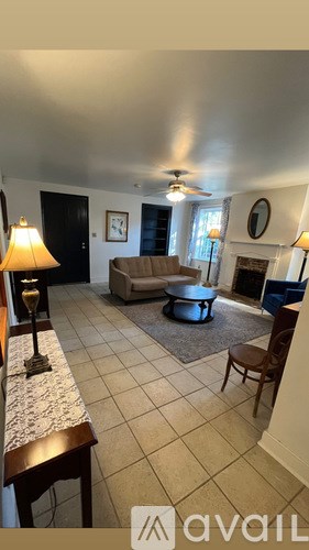 A living room with a couch, chair, and a table with a lamp on it.