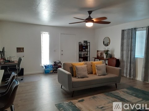 A living room with a grey couch and a ceiling fan.