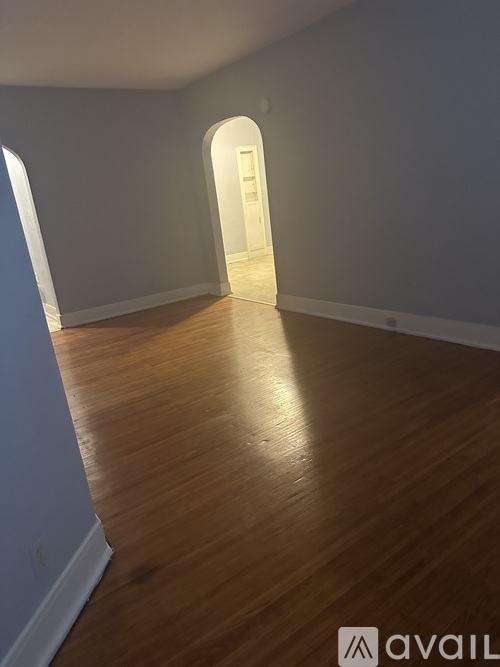 A room with wooden flooring and a white archway.