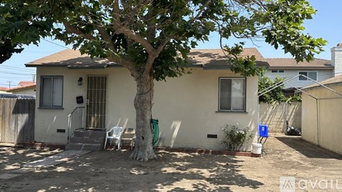 A tree in front of a house with a sign that says "available".