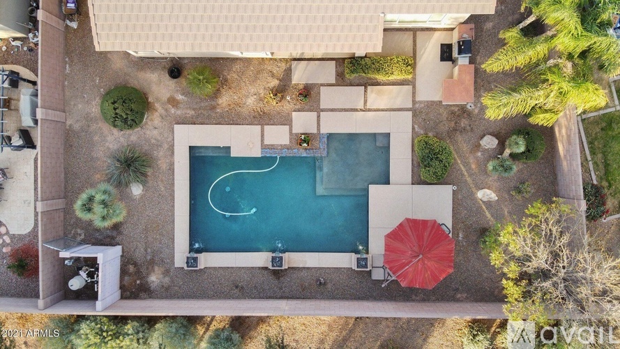 A pool with a red umbrella and a white bench.