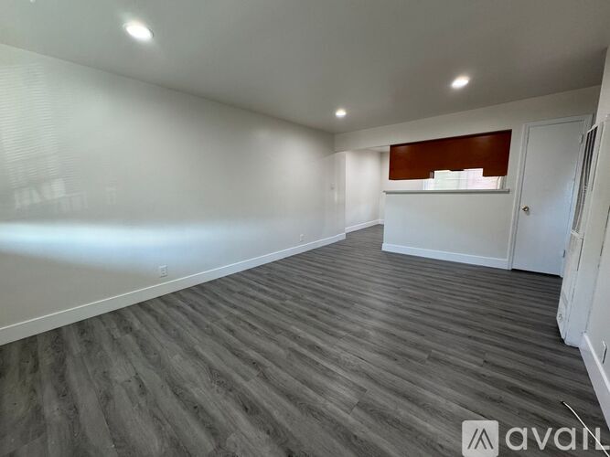 A spacious room with wooden flooring and white walls.