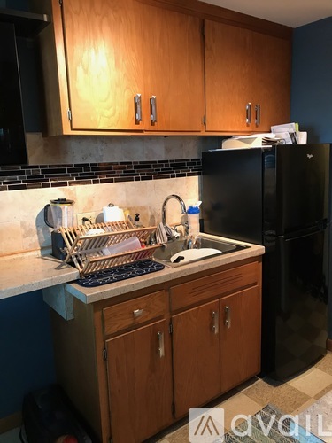 A kitchen with wooden cabinets and a black fridge.