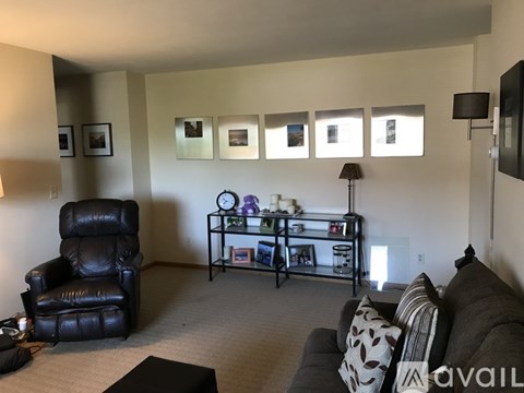 A living room with a black leather chair and a grey couch.