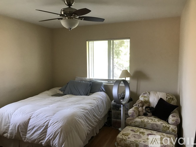 A bedroom with a bed, chair, and window.