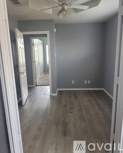 A room with a ceiling fan and wooden flooring.