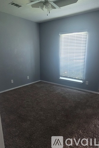 A room with a carpeted floor and a window with blinds.