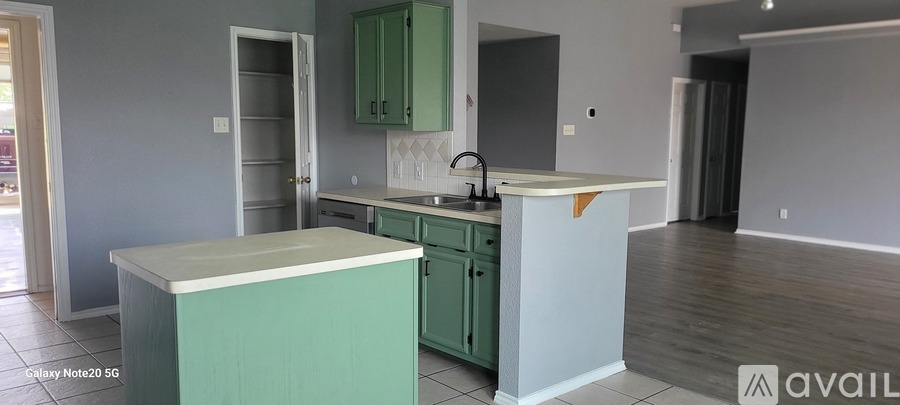 A kitchen with green cabinets and a white countertop.