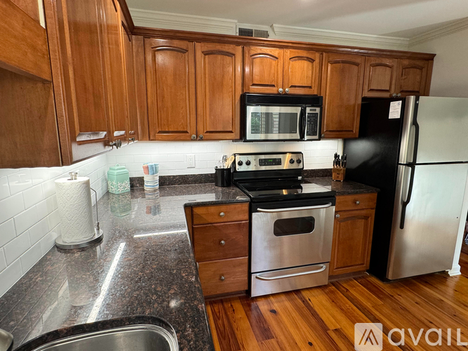 A kitchen with wooden cabinets and a black refrigerator.