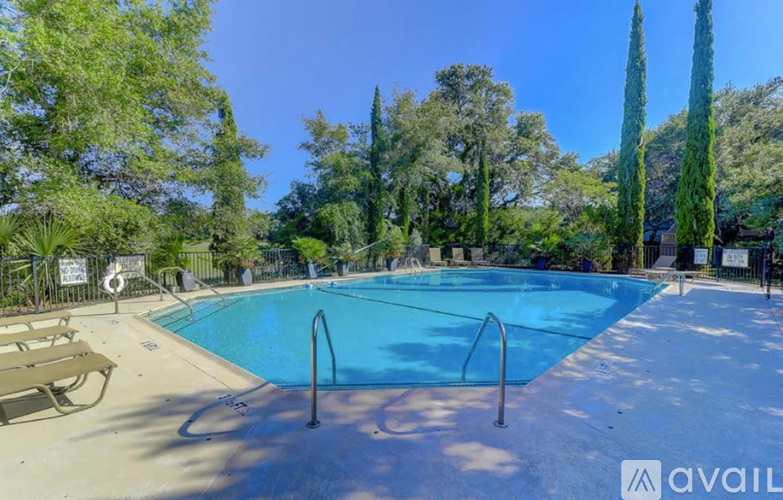 A swimming pool surrounded by trees and a bench.