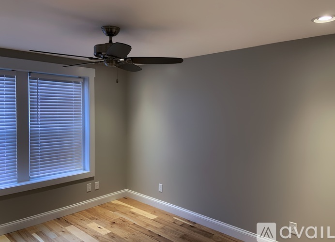 A room with a ceiling fan and a window with blinds.